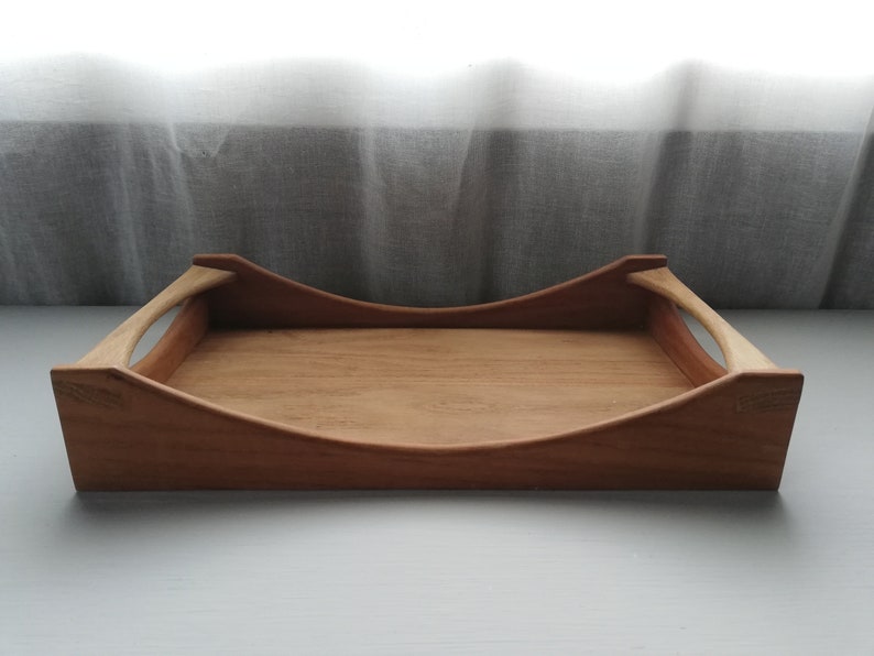 May include: A wooden serving tray with two curved handles. The tray is made of light brown wood and has a natural finish.
