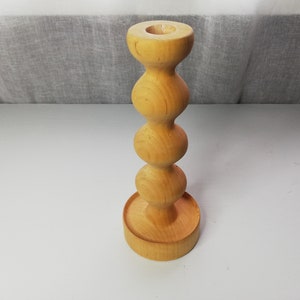 Puede incluir: Un portavelas de madera con un dise&ntilde;o redondeado y bulboso. El portavelas est&aacute; hecho de madera marr&oacute;n claro y tiene un acabado liso.