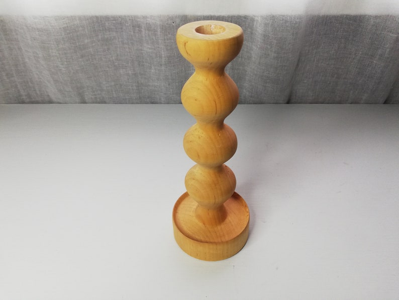 Puede incluir: Un portavelas de madera con un dise&ntilde;o redondeado y bulboso. El portavelas est&aacute; hecho de madera marr&oacute;n claro y tiene un acabado liso.