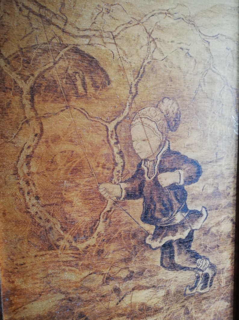 May include: A woodburned image of a child wearing a hat and coat, ice skating on a frozen lake. The child is holding a rope attached to a tree branch, suggesting they are swinging on a rope swing.