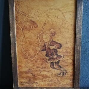 May include: A framed wood-burned artwork depicting a child wearing a hat and coat, standing in a snowy forest scene. The artwork is signed "SUME" in the bottom left corner.