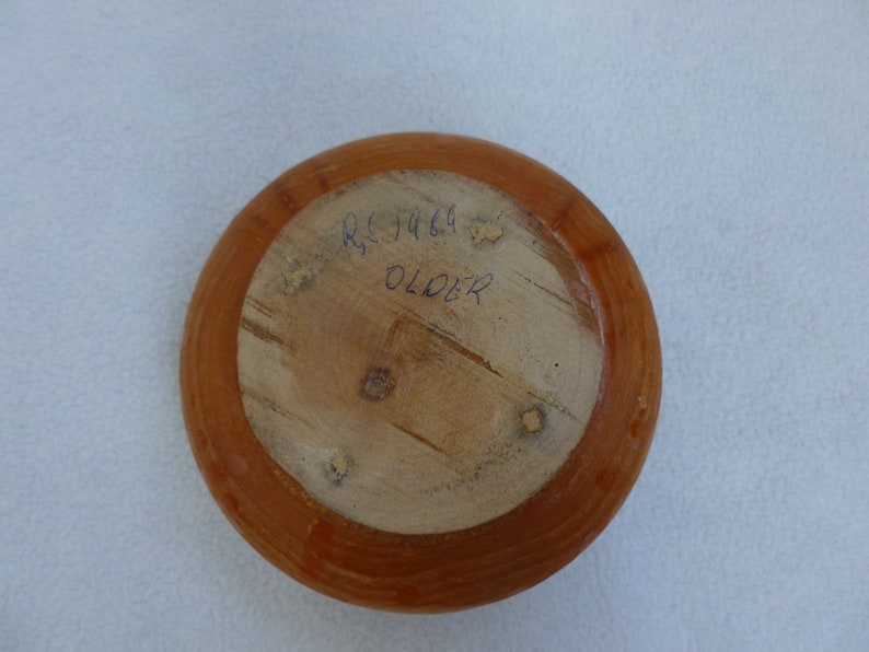 May include: A wooden bowl with a brown stain. The bottom of the bowl has the text "RSJ 1469 OLDER" written in blue ink.