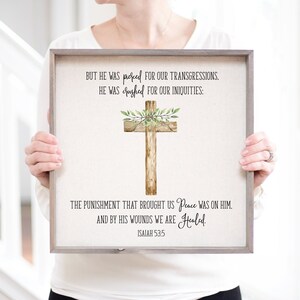 May include: A framed print with a watercolor cross and a quote from Isaiah 53:5. The quote reads: "But he was pierced for our transgressions, he was crushed for our iniquities: The punishment that brought us peace was on him. And by his wounds we are healed."