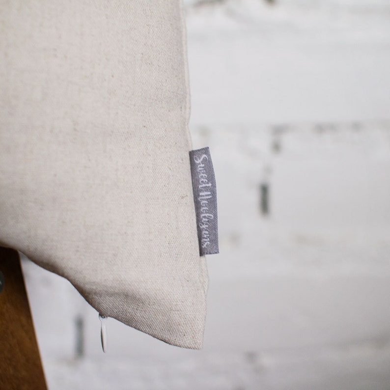 May include: A close-up of a beige pillowcase with a gray label that reads "Sweet Indulgence".