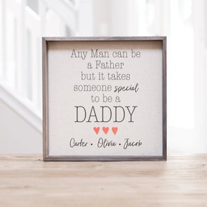 May include: A framed canvas sign with the text "Any Man can be a Father but it takes someone special to be a DADDY" with three pink hearts below the word "DADDY" and the names "Carter. Olivia. Jacob" below the hearts.