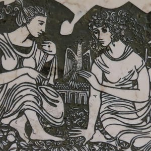 Puede incluir: Un relieve en blanco y negro que representa a dos mujeres con vestimenta clásica. Una mujer sostiene una tela, mientras que la otra señala una representación detallada de un águila. El fondo presenta elementos arquitectónicos estilizados y follaje.