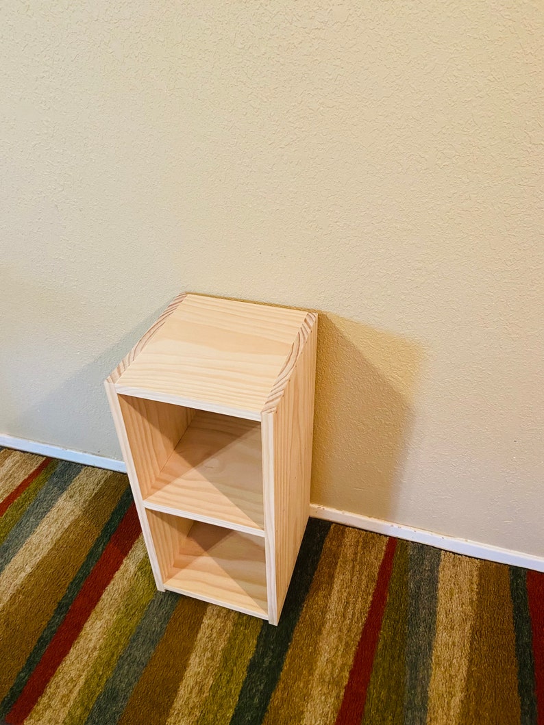Op de afbeelding: Een houten boekenkast met twee planken en een natuurlijke houtkleur. De boekenkast is gemaakt van massief hout en heeft een eenvoudig, modern ontwerp.