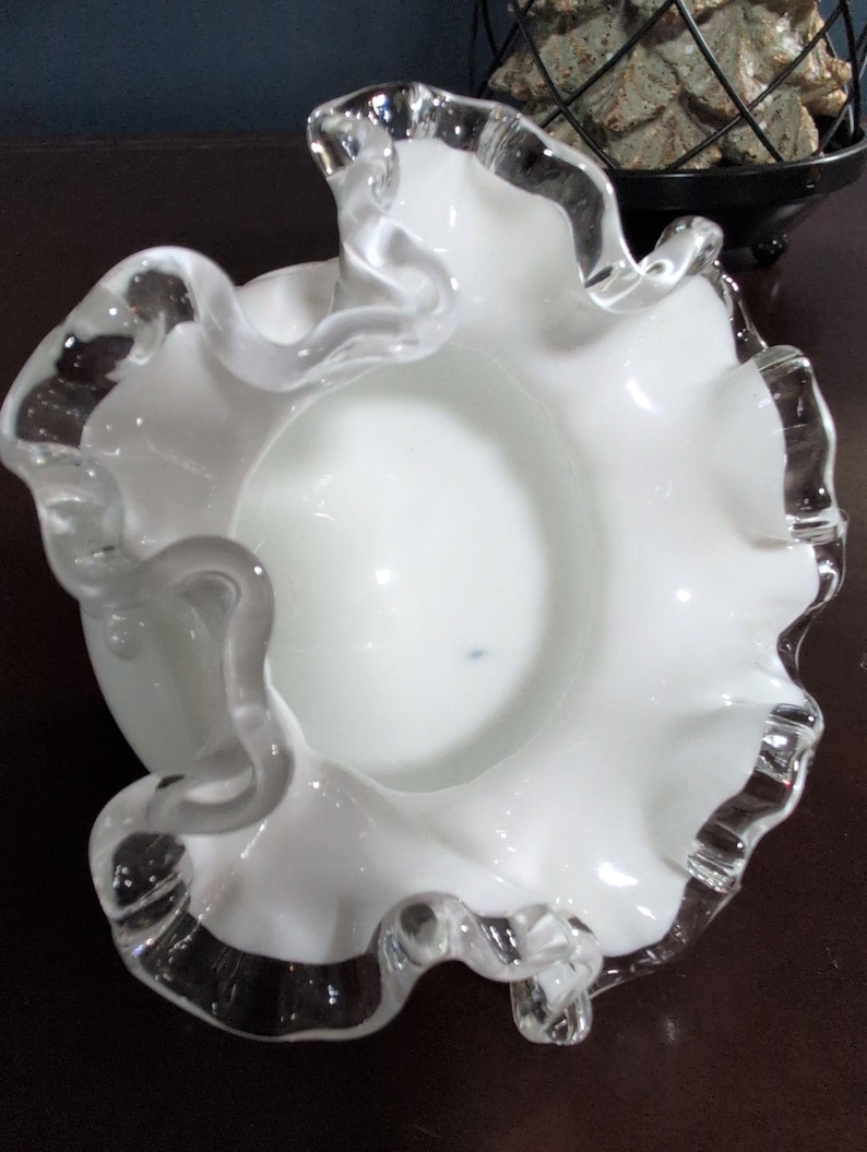 May include: White glass bowl with a ruffled edge. The bowl is made of clear glass with a white interior.