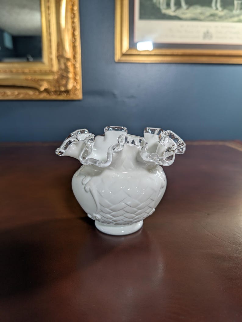 May include: A white glass vase with a ruffled, silver-trimmed rim. The vase has a textured, diamond-shaped pattern and a rounded base.