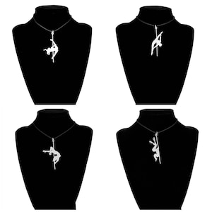 Puede incluir: Cuatro expositores de terciopelo negro con collares plateados que representan una silueta de una persona bailando en un poste. Los collares se exhiben sobre un fondo blanco.