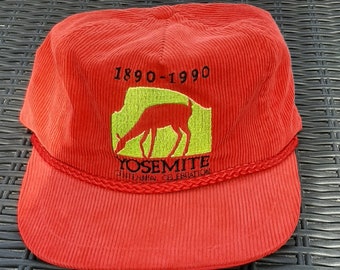 May include: Red corduroy baseball cap with a green and yellow embroidered logo that says "Yosemite Centennial Celebration 1890-1990" and features a deer.