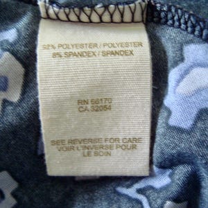 May include: A close-up shot of a fabric label. The label states "92% POLYESTER/POLYESTER 8% SPANDEX/SPANDEX", along with the codes "RN 66170" and "CA 32054". It also includes the text "SEE REVERSE FOR CARE VOIR L'INVERSE POUR LE SOIN".