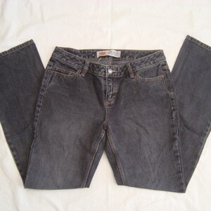 Puede incluir: Vaqueros de mezclilla gris oscuro con cintura de tiro bajo y corte de pierna bootcut. Los pantalones incluyen cierre de botón, cremallera, dos bolsillos delanteros y una etiqueta interior visible que dice Low Rise Boot Cut.
