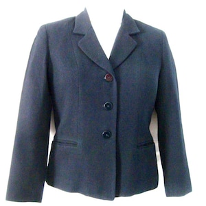 Pode incluir: Um blazer azul-marinho escuro com gola de lapela, mangas compridas e fecho frontal com três botões escuros. A peça inclui dois bolsos horizontais com debrum na cintura e costuras verticais para um ajuste estruturado e elegante.