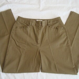 May include: Olive green trousers featuring a structured waistband with belt loops, a front zipper fly closure, and two slanted side pockets. These straight-leg pants are crafted from a solid-colored fabric with visible stitching along the seams.