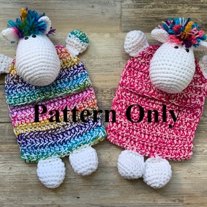 May include: Two crocheted unicorn amigurumi toys. One is rainbow colored and the other is pink. Both have white bodies and white feet. The text "Pattern Only" is visible in the image.