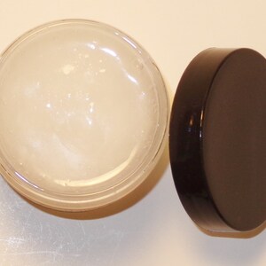 May include: A clear glass jar containing a white, creamy substance. The jar has a black lid.