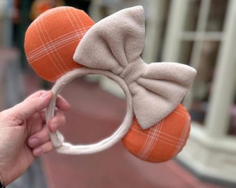 May include: Orange and white plaid Minnie Mouse ears with a large white bow.