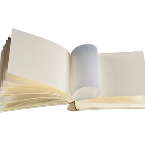 K&ouml;nnte beinhalten: Ein offenes leeres Buch mit cremefarbenen Seiten. Das Buch liegt flach mit aufgef&auml;cherten Seiten.