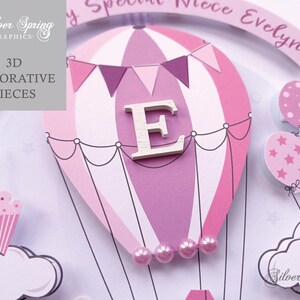 May include: A pink and white hot air balloon with a wooden letter E in the center. The balloon is decorated with pink and white stripes and a string of pink flags. The balloon is surrounded by pink and white clouds and stars. The text "My Special Niece Evelyn" is written on a banner above the balloon.