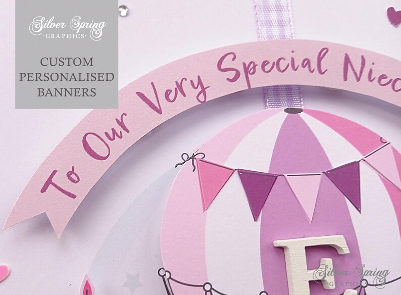 May include: A pink and purple hot air balloon banner with the text "To Our Very Special Niece" and the letter "F" in white. The banner is decorated with pink and purple pennants.