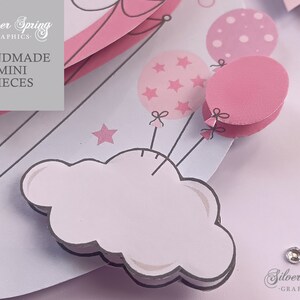 May include: Pink and white paper craft with a cloud, stars, and balloons. The balloons have a polka dot pattern, a star pattern, and are solid pink. The text "Handmade Mini Pieces" is on the craft.