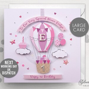 May include: A pink and white hot air balloon with a letter "E" on it, surrounded by pink clouds and stars. The card says "To Our Very Special Niece Evelyn" and "Happy 1st Birthday".