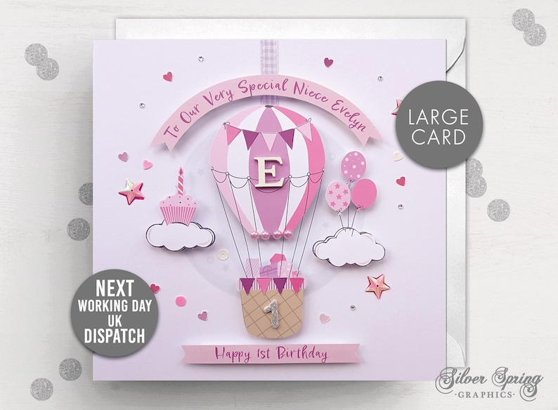 May include: A pink and white hot air balloon with a letter "E" on it, surrounded by pink clouds and stars. The card says "To Our Very Special Niece Evelyn" and "Happy 1st Birthday".