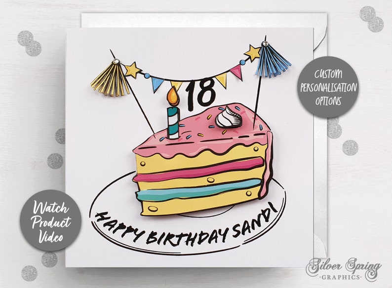 May include: A white card with a colorful birthday cake illustration. The cake is decorated with pink frosting, sprinkles, and a single candle. The cake is on a plate with the words 'Happy Birthday Sandi' written around it. The card also has a banner with stars and flags, and the number 18 on the cake. The card has a gray circle with the text 'Custom Personalisation Options' in the top right corner and a gray circle with the text 'Watch Product Video' in the bottom left corner.