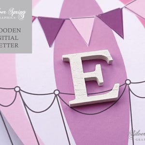 May include: White wooden letter E on a pink and white hot air balloon background with purple and pink pennant flags.  Wooden Initial Letter.