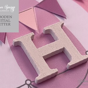 May include: White wooden letter H on a pink and white background with a banner design. The letter is a craft supply for scrapbooking, card making, and other DIY projects.