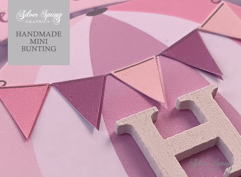 May include: Pink and white bunting with a wooden letter H. The bunting is made of felt and has a textured surface. The letter H is painted white and has a textured surface. The bunting is hanging from a string. The text "HANDMADE MINI BUNTING" is visible in the image.