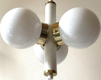 Könnte beinhalten: Ein moderner weißer und goldener Kronleuchter mit vier runden weißen Glasschirmen.