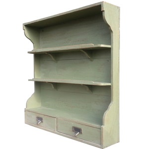 Peut inclure: Une étagère murale en bois vert avec trois étagères et deux tiroirs. L'étagère a un aspect rustique et vieilli et est parfaite pour exposer des objets décoratifs ou ranger de petits objets.