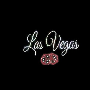 May include: A black background with the words "Las Vegas" in white rhinestones and a red dice with white dots in the center.