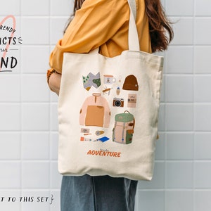 May include: A white canvas tote bag with a colorful illustration of camping gear and the text "born for adventure".