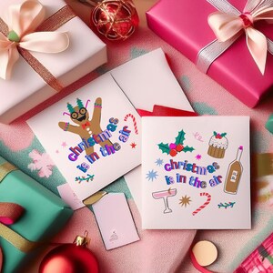 K&ouml;nnte beinhalten: Zwei Weihnachtskarten mit bunten Illustrationen und dem Text "Christmas is in the air". Eine Karte zeigt einen Lebkuchenmann und die andere einen Cocktail, einen Zuckerstock und einen Kuchen.