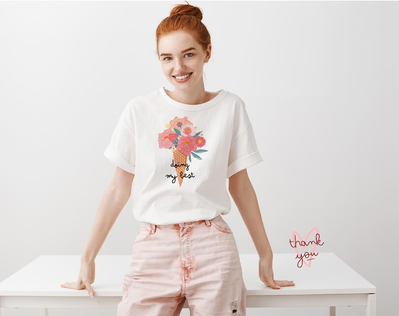 May include: White t-shirt with a floral ice cream cone graphic and the text "doing my best".
