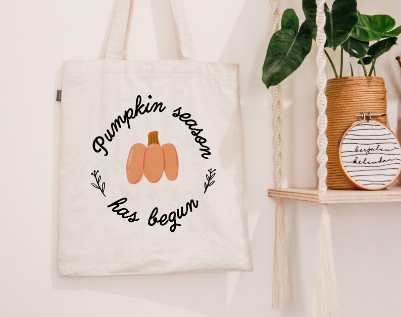 May include: A white canvas tote bag with the text "Pumpkin season has begun" in black lettering and a small orange pumpkin illustration.