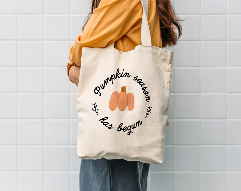 May include: A white tote bag with the text "Pumpkin season has begun" and a drawing of a pumpkin.