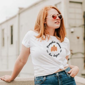 May include: A white t-shirt with the text "Pumpkin season has begun" and a small illustration of a pumpkin.