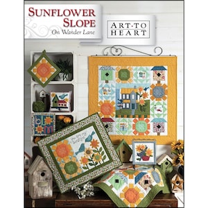 May include: A display of handmade quilted items with a sunflower theme. The items include a wall hanging, a small pillow, a pot holder, and a table runner. The color palette includes yellow, orange, green, and blue. The text "Sunflower Slope" is visible.