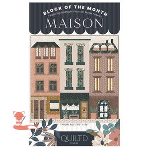 May include: A quilt featuring a cityscape design with the text "BLOCK OF THE MONTH" and "MAISON". The quilt showcases buildings with windows and doors in shades of pink, green, and brown. The throw size is 60" x 59".