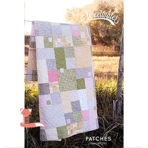 May include: A patchwork quilt with squares of pink, green, yellow, and gray fabric. The quilt is hanging on a fence with the text "Sweetwater" and "PATCHES Item #R295" at the bottom.