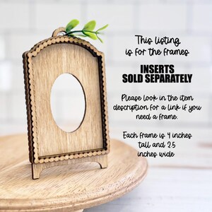 May include: A light brown wooden arched frame with a scalloped edge and a central oval cutout. The frame features a small green leaf accent at the top. Text on the image states: This listing is for the frames, INSERTS SOLD SEPARATELY, 4 inches tall and 2.5 inches wide.