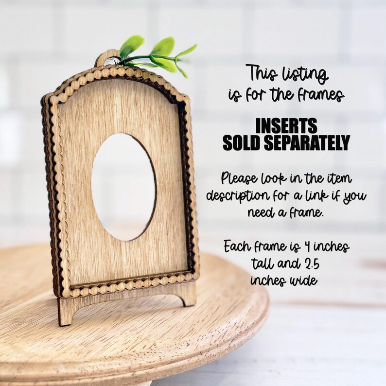 May include: A light brown wooden arched frame with a scalloped edge and a central oval cutout. The frame features a small green leaf accent at the top. Text on the image states: This listing is for the frames, INSERTS SOLD SEPARATELY, 4 inches tall and 2.5 inches wide.