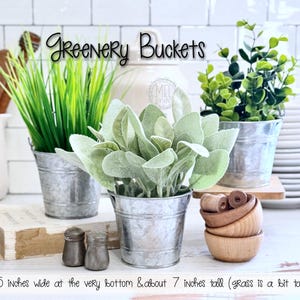 May include: Three galvanized metal buckets filled with greenery. The buckets are 2.15 inches wide at the bottom and about 7 inches tall. The image also includes small wooden bowls, salt and pepper shakers, and the text "Greenery Buckets".