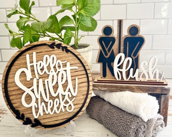 Funny bathroom signs, this is a set.  Round Hello sweet cheeks 6" with tripod & Flush with potty stick figures funny bathroom decor