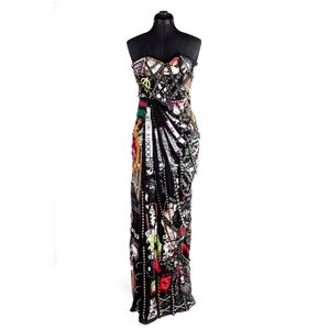 May include: A black strapless gown with a long, flowing skirt. The gown is covered in patches of fabric, including denim, leather, and printed cotton. The patches are arranged in a random pattern and feature a variety of colors, including red, green, blue, and yellow. The gown is accented with silver studs and chains.