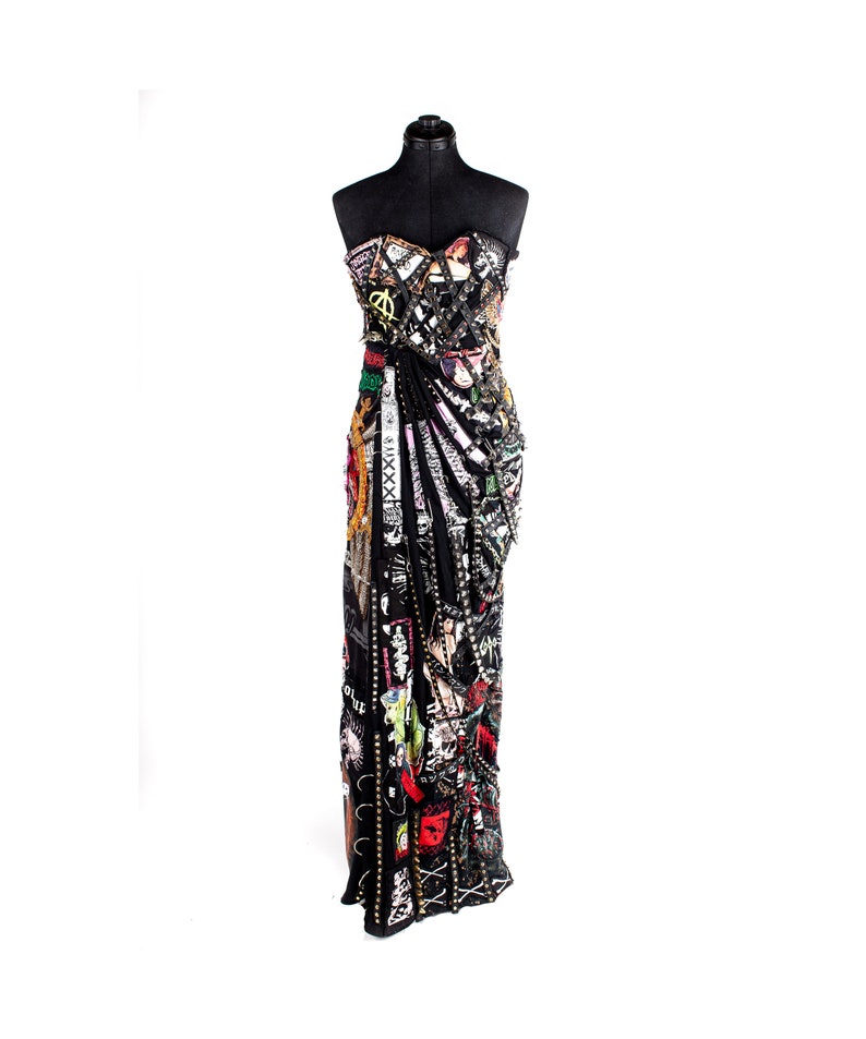 May include: A black strapless gown with a long, flowing skirt. The gown is covered in patches of fabric, including denim, leather, and printed cotton. The patches are arranged in a random pattern and feature a variety of colors, including red, green, blue, and yellow. The gown is accented with silver studs and chains.